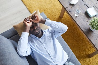 Psikiyatristlerin kanepesinde uzanan ve terapi seansında duygularını tarif eden gözleri kapalı rahatsız genç siyahi adamın tam üstünde.