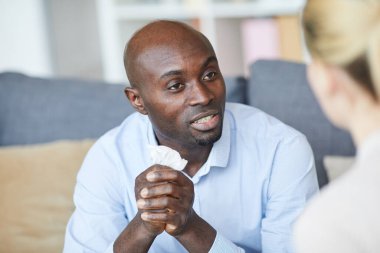 Elinde peçeteyle gezen kel bir genç adam çözüm ararken terapistle konuşuyor.