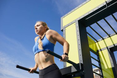 Paralel parmaklıklarda tek başına antrenman yapan, örgülü güçlü bir kız.
