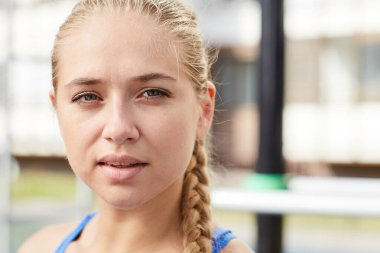 İçeriğin portresi. Açık hava spor sahasında duran örgülü güzel sarışın kız.