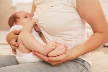 Yeni doğan kızını anne sütüyle besleyen genç bir anne görüntüsü.
