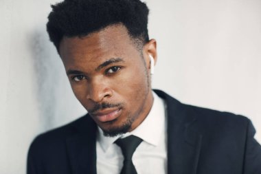 Bağlantı için kablosuz kulaklık takan takım elbiseli, vahşi, Afro-Amerikalı iş adamının portresi.