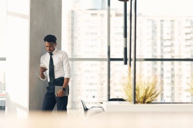 Modern iş lobisinde duruyor ve interneti alet edevat üzerinde kullanıyor.