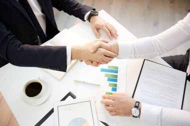 Formalite icabı tanınmayan girişimcilerin yüksek açılı görüşü, sözleşme imzalandıktan sonra evraklar ve el sıkışmalarıyla masada oturmaları
