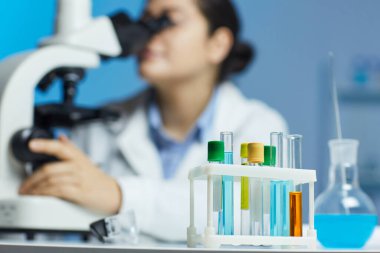 Laboratuvar teknisyeninin rafına koyulan renkli tıbbi örneklerle dolu test tüplerinin yakın çekimleri.