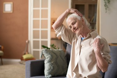 Sabahları oturma odasındaki kanepede otururken kıdemli kadın egzersiz yapıyor.