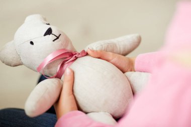 Tanımlanamayan üzgün kızın elinde kurdeleyle korku ve yalnızlık hisseden bir oyuncak ayı.