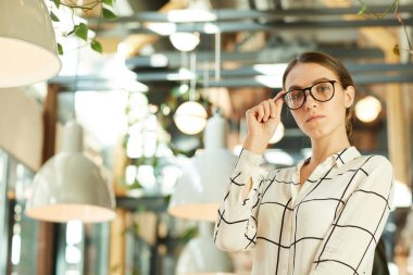Fikri düşünürken gözlüğü ayarlayan kareli gömlek konusunda kendine güvenen genç yaratıcı uzmanların portresi.