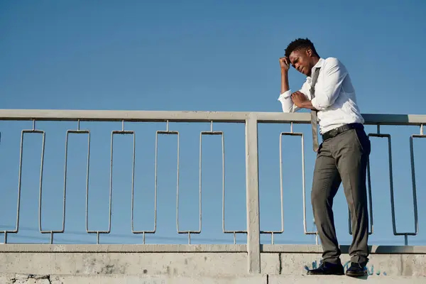 Young depressed man standing on the bridge and thinking about suicide