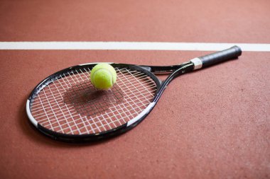 Kırmızı stadyum zeminine yerleştirilen raket ve top gibi tenis oyuncusunun yakın çekim ekipmanları, tenis oyunu konsepti