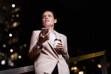 Düşük görüşlü orta yaşlı iş kadını kendi başarısına güvenen gece açık merdivenlerde duran ve alet kullanan.