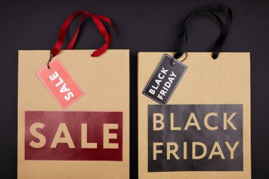 Satış ve Kara Cuma 'ya adanmış siyah ve kırmızı renkli harf dolu alışveriş poşetleri.