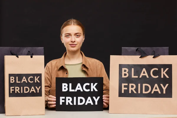 stock image Portrait of content attractive young store seller working on Black Friday: she sitting with tablet at table