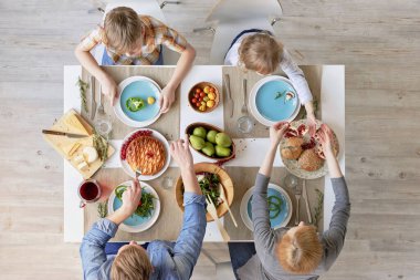 Ebeveynlerin ve çocukların mutfak masasında oturup lezzetli bir öğle yemeği yediği en iyi manzara: taze sebze salatası, meyve, peynir ve ev yapımı turta.