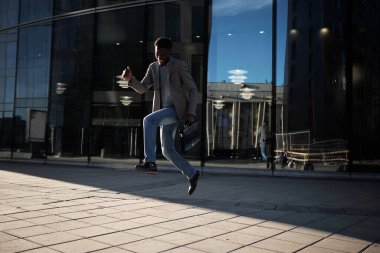 Mesai bitiminde. Afro-Amerikalı bir ofis çalışanı. Kaldırımdan atlayıp gülümsüyor.