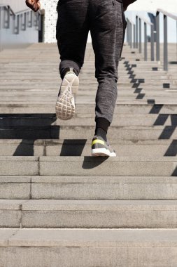Etkili adım çalışması çalışması. Dışarıdaki beton merdivenlerden koşarak çıkan tanınmayan erkek sporcunun bacaklarının arkası.