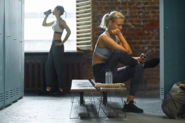 İki rahat genç kadın spor salonunda yatay çekim yapıyor.