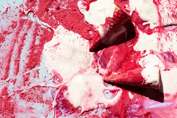 Melted ice-cream mess. Conceptual photo of waffle cones and melted strawberry ice-cream with pink powder, top view