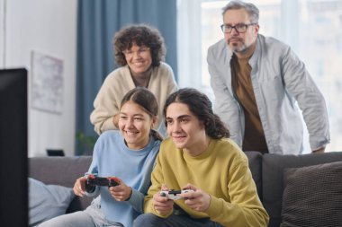 Çocuklar evde aileleriyle oyun oynamak için joystickleri kullanıyorlar.