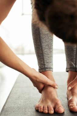 Öne doğru eğilirken el bileği tutan tanınmayan bir kadının yakın çekimi.
