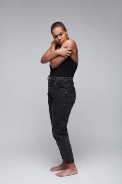 Korku ve güvensizlik hissederken, siyah hayatlar yüzünden kendini kucaklayan, yalıtılmış arka planda dikilen siyah saçlı, korkmuş genç bir kadın.