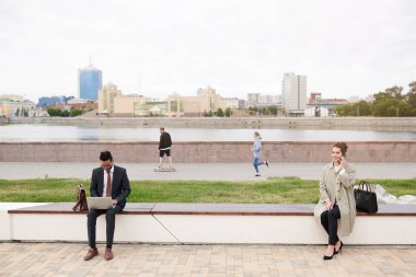 Şehir parkında bankta oturan meşgul insanlar Coronavirus karantinası sırasında güvenli mesafeyi koruyorlar.