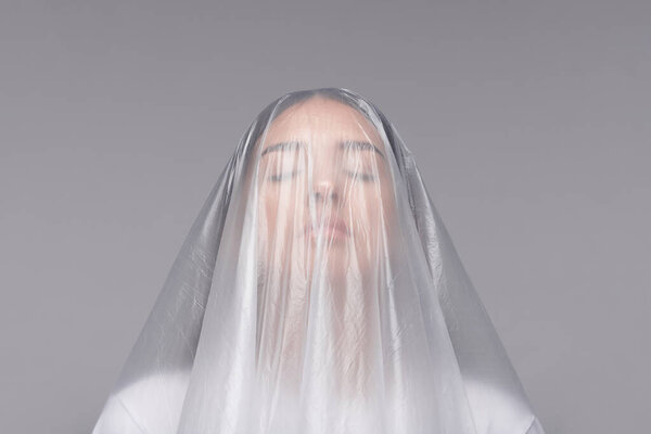 Young woman with closed eyes suffering from bad ecology, she covered with plastic bag