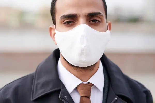 Close-up of Arabian man using mask to protect himself against coronavirus outdoors
