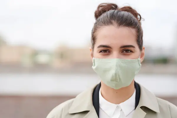 Portrait of attractive young businesswoman in cloth mask walking outside during coronavirus using protection thing