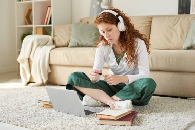 Tembel, kızıl saçlı, kablosuz kulaklıkla müzik dinleyen ve sınava hazırlanmak yerine evde tırnaklarını boyayan bir kız.