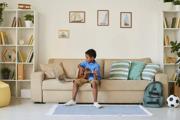 Soustředěný Afroamerický Chlapec Modré Košili Sedí Pohovce Učí Hrát Kytaru — Stock fotografie