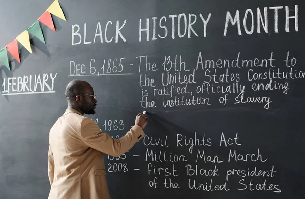 Siyah Tarih Ayı hakkında bir ders sırasında tahtaya yazı yazan Afrikalı Amerikalı öğretmen