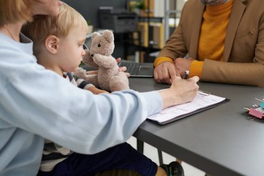 Genç anne sosyal hizmetlere yaptığı ziyarette evlatlık belgeleri dolduruyor.