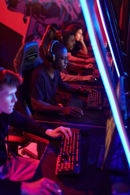 Group of serious young multi-ethnic men playing video games while participating in esports tournament, neon light clipart