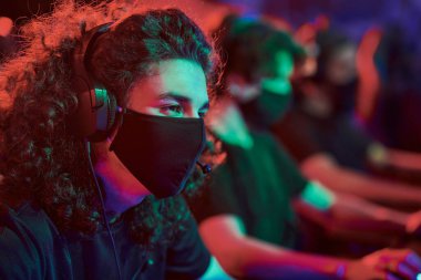 Kıvırcık saçlı, bez maskeli ve kulaklıklı beyaz adam ihracat yarışmasına katılıyor.