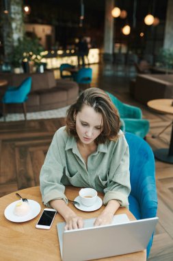 Modern kafede masada oturan ve projeyi telefonda tartışırken kahve içen meşgul genç sakallı adam.