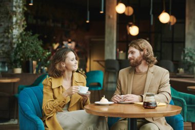 Düşünceli genç sakallı SMM yöneticisi kahve içiyor ve kafede çalışırken müşterilerin mesajlarını düşünüyor.