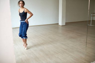 Bale ayakkabılı genç bayan dansçı. Pointer tekniği uyguluyor ve dans stüdyosunda aynaya bakıyor.