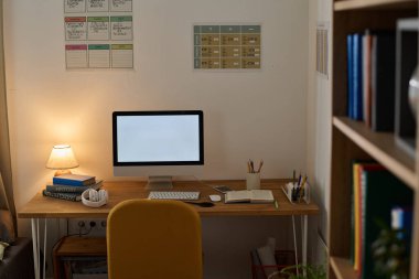 Masasında bilgisayar monitörü olan bir gencin çalışma odası.