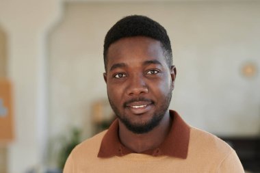 Ofiste duran sakallı ve süveter giyen Afro-Amerikan genç adamın portresi.