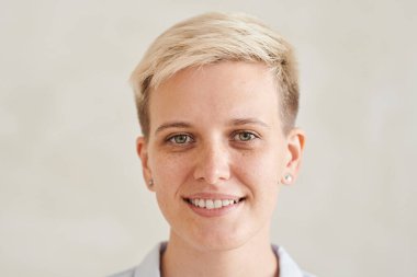 Beyaz dişleri ve çilleri olan, izole edilmiş arka planda kameraya bakan gülümseyen sarı saçlı kızın yüzü.