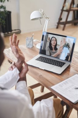 Modern Afro-Amerikan doktorların dizüstü bilgisayarın önünde otururken çevrimiçi video görüşlerini gösteren dikey yüksek açılı görüntüleri.