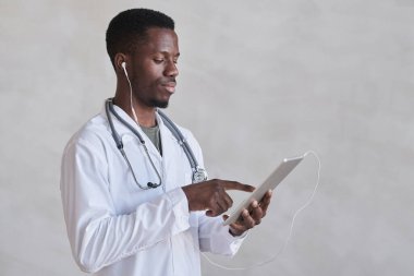 Dijital tablet kullanarak kulaklık takan genç Afrikalı Amerikalı bir doktor.