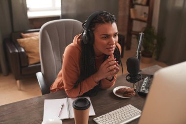 Modern kadın video blogcusunun tavan arasında oturup son video içeriği hakkındaki yorumlarını okuduğu yüksek açılı yatay bir çekim.