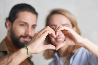 Yakışıklı genç adam ve çekici sarışın kadının el kalp hareketlerini yakından çek.