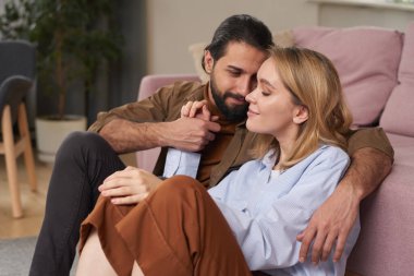 Sakallı yakışıklı genç adam, güzel kız arkadaşıyla evde vakit geçiriyor ve birlikte oturma odasında dinleniyor.