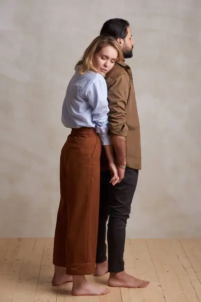 Full body studio portrait of young woman in love standing relaxed behind her boyfriends back leaning on him with eyes closed, copy space