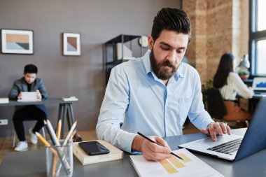 Beyaz adamın ofiste çalışıp para birimi istatistiklerini grafikleri ve grafikleri kullanarak analiz ederken yatay görüntüsü.