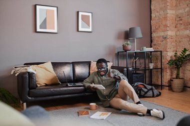 Genç bir adamın oturma odasında oturmuş para ticareti yaparken büyük kar elde etmesinin uzun vadeli görüntüsü.