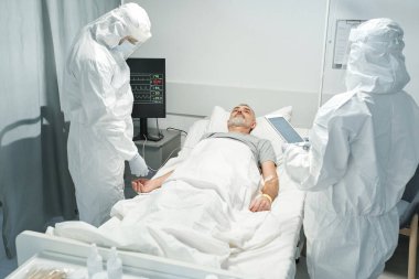 Korunaklı kıyafetler giyen iki tanınmayan doktor Coronavirus hastası ile çalışıyor.